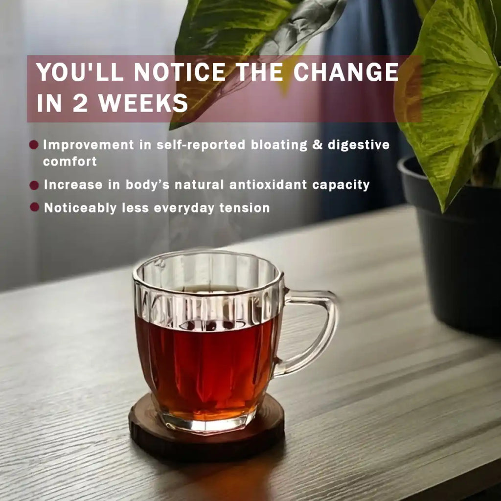 A clear glass mug filled with amber tea sits on a round wooden coaster on a tabletop, with a potted plant in the background and promotional text overlaid on the left.