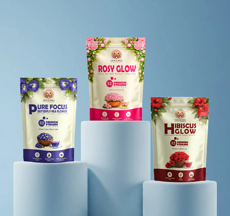 Three stand-up pouches of flower-themed supplement products displayed on light blue pedestal blocks against a soft blue gradient background. The packages are labeled Pure Focus (purple), Rosy Glow (pink), and Hibiscus Glow (red), with cream backgrounds and floral illustrations.